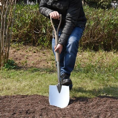 Un homme donne des coups de pelle dans son potager